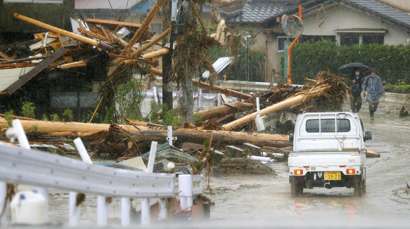 People carry a refrigerator out of a flooded office in Hitoyoshi city, Kumamoto prefecture, southwestern Japan, Tuesday, July 7, 2020. Floodwaters flowed down streets in southwestern Japanese towns hit by deadly rains that were expanding across the region Tuesday. (Yuki Sato/Kyodo News via AP)