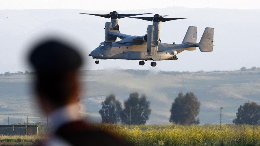 An Italian Carabinieri officer looks on as an MV-22 Osprey vertical take off and lift aircraft lands with on board US General Carter Ham, Commander of the United States military mission in Libya, in the Sigonella airbase, Sicily, Thursday, March 24, 2011. (AP Photo/Andrew Medichini)