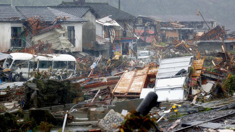 People carry a refrigerator out of a flooded office in Hitoyoshi city, Kumamoto prefecture, southwestern Japan, Tuesday, July 7, 2020. Floodwaters flowed down streets in southwestern Japanese towns hit by deadly rains that were expanding across the region Tuesday. (Yuki Sato/Kyodo News via AP)