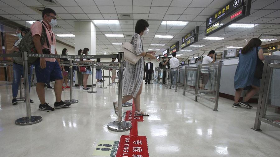 An epidemic prevention staff member shows disinfection measures to participants during a mock trip abroad at Taipei Songshan Airport in Taipei, Taiwan, Tuesday, July 7, 2020. Dozens of would-be travelers acted as passengers in an activity organized by Taiwan’s Civil Aviation Administration to raise awareness of procedures to follow when passing through customs and boarding their plane at Taipei International Airport. (AP Photo/Chiang Ying-ying)
