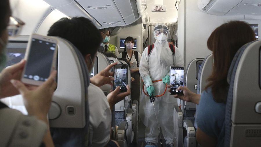 An epidemic prevention staff member shows disinfection measures to participants during a mock trip abroad at Taipei Songshan Airport in Taipei, Taiwan, Tuesday, July 7, 2020. Dozens of would-be travelers acted as passengers in an activity organized by Taiwan’s Civil Aviation Administration to raise awareness of procedures to follow when passing through customs and boarding their plane at Taipei International Airport. (AP Photo/Chiang Ying-ying)