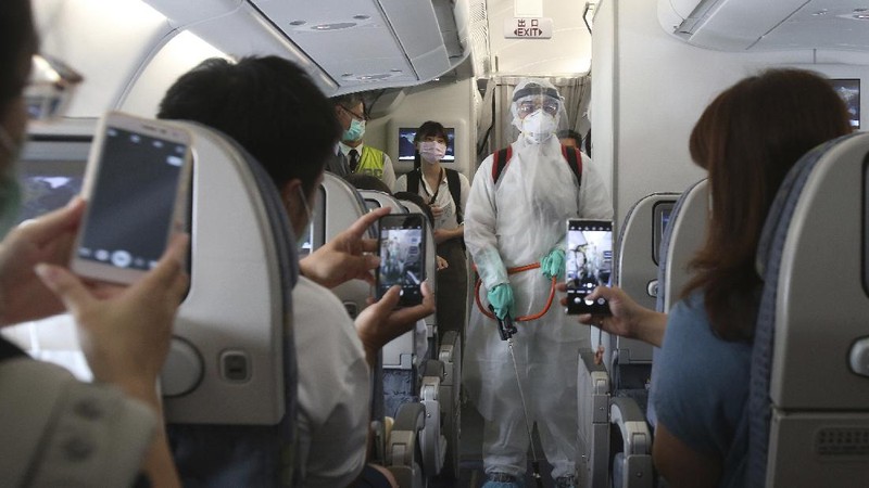 An epidemic prevention staff member shows disinfection measures to participants during a mock trip abroad at Taipei Songshan Airport in Taipei, Taiwan, Tuesday, July 7, 2020. Dozens of would-be travelers acted as passengers in an activity organized by Taiwan’s Civil Aviation Administration to raise awareness of procedures to follow when passing through customs and boarding their plane at Taipei International Airport. (AP Photo/Chiang Ying-ying)