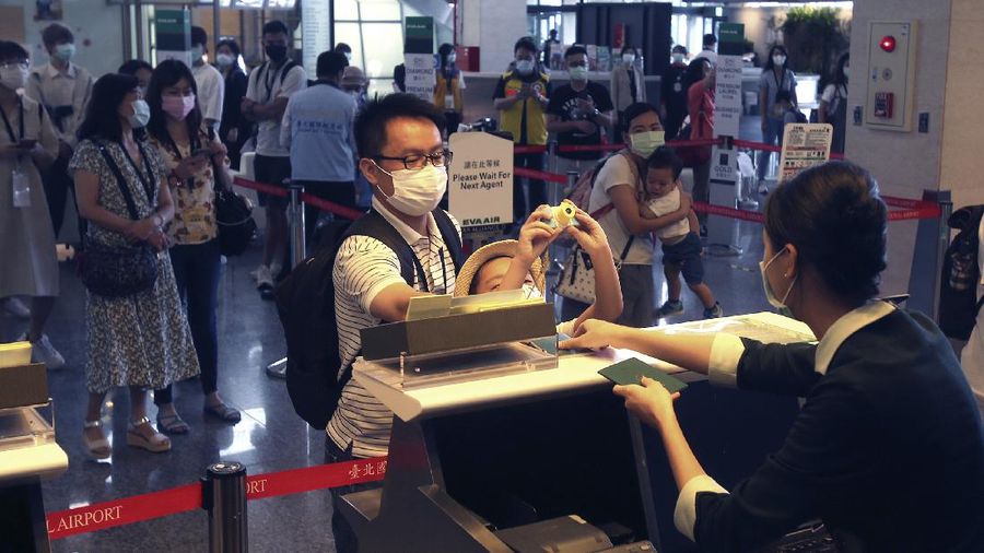 An epidemic prevention staff member shows disinfection measures to participants during a mock trip abroad at Taipei Songshan Airport in Taipei, Taiwan, Tuesday, July 7, 2020. Dozens of would-be travelers acted as passengers in an activity organized by Taiwan’s Civil Aviation Administration to raise awareness of procedures to follow when passing through customs and boarding their plane at Taipei International Airport. (AP Photo/Chiang Ying-ying)