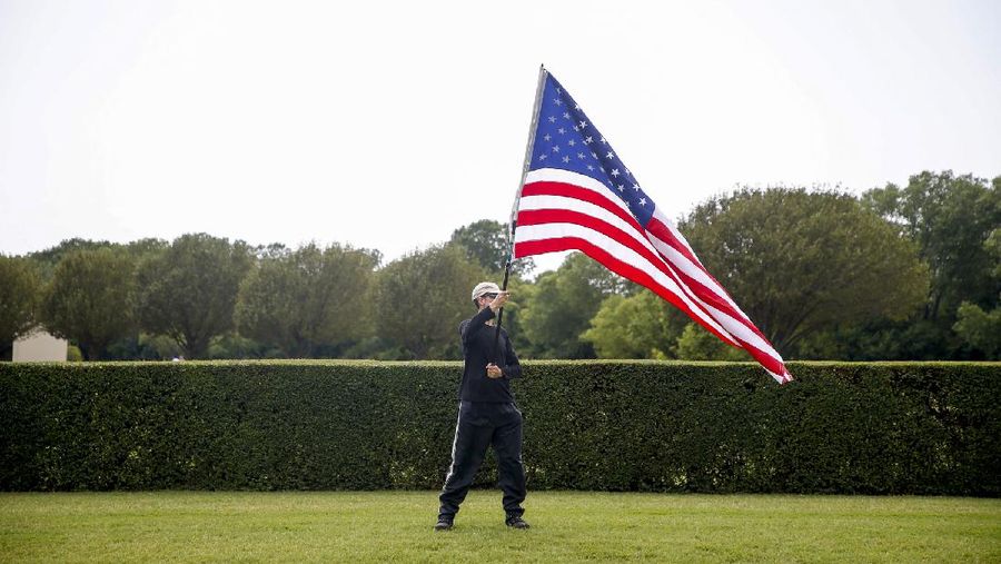 A spectator waves an American flag during the processional for Tulsa Police Sgt. Craig Johnson in front of Floral Haven Cemetery on Thursday, July 9, 2020, in Tulsa, Okla. Johnson was shot during a traffic stop on June 29. (Ian Maule/Tulsa World via AP)