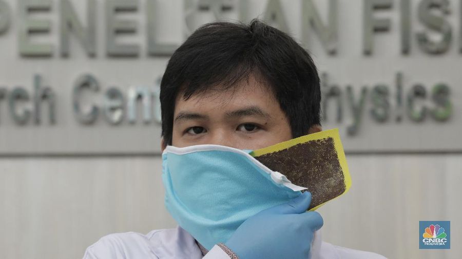 Tim Peneliti Fisika LIPI, Puspitek Tangerang Selatan berhasil mengembangkan masker kain disinfektor berlapis tembaga yang mampu membunuh virus Covid-19 dalam waktu 4 jam. Jumat (10/7/20). CNBC Indonesia/Tri Susilo Lembaga Ilmu Pengetahuan Indonesia (LIPI) melakukan riset pada masker kain sebagai upaya penanganan Covid-19 di Indonesia. Inovasi masker ini diperuntukan bagi masyarakat umum, bukan tenaga medis. Peneliti Pusat Penelitian Fisika LIPI Deni Shidqi Khaerudini menyatakan, timnya sedang mengembangkan masker kain disinfektor berbasis lapisan tembaga yang diyakini anti Covid-19. Ini berdasarkan beberapa penelitian terkait tembaga sebagai anti-microbial agent. Penelitian tersebut di antaranya menunjukkan bahwa tembaga telah dikenal sebagai anti-microbial agent (agen anti mikroba) sejak zaman Mesir dan Yunani kuno, seperti untuk perawatan luka dan sterilisasi air. Selain itu, ditemukan terjadinya perusakan bakteri maupun virus akibat kontak dengan tembaga (contact killer), meski berbeda-beda tergantung jenis mikroorganisme. Secara umum, mekanisme perusakan terjadi dengan ion-ion tembaga yang mudah terlepas setelah bakteri atau virus menempel pada lapisan tembaga. Hal ini mengakibatkan kerusakan pada dinding sel dan degradasi DNA atau RNA, sehingga mikroba tidak mampu reproduksi yang berujung pada kematian sel tersebut. Terkait SARS-CoV-2 atau virus corona penyebab Covid-19, penelitian terbaru menunjukkan bahwa virus corona hanya mampu bertahan selama 4 jam di permukaan tembaga. Riset ini juga didasari efektivitas penyaringan (filter) mikroorganisme terhadap masker kain yang selama ini umum digunakan masyarakat untuk mencegah penularan Covid-19. Diketahui, virus corona berdiameter 0,065-0,125 mikron. Penelitian efektivitas filter masker kain didasarkan pada mikroorganisme B. Atrophaeus yang berdiameter 0,9-1,25 mikron. Hasilnya, masker kain satu lapis memiliki kemampuan filter 69,42 persen dan yang dua lapis sebesar 70,66 persen. Dengan demikian, jika dibandingkan dengan virus corona yang memiliki diameter 10 kali lipat lebih kecil dari bakteri B. Atrophaeus, maka kemampuan filter masker kain terhadap virus corona jauh lebih rendah. (CNBC Indonesia/ Tri Susilo)