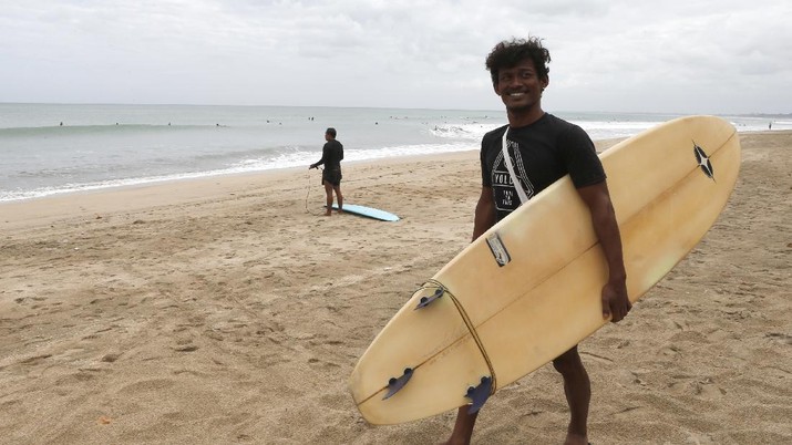 Pantai di Bali Tourists wearing face masks carry their surfboard at Kuta beach, Bali, Indonesia on Thursday, July 9, 2020. Indonesia's resort island of Bali reopened after a three-month virus lockdown Thursday, allowing local people and stranded foreign tourists to resume public activities before foreign arrivals resume in September.(AP Photo/Firdia Lisnawati)