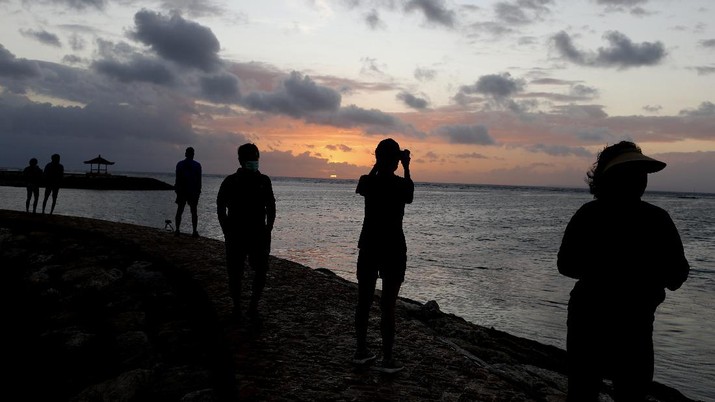 Pantai di Bali Tourists wearing face masks carry their surfboard at Kuta beach, Bali, Indonesia on Thursday, July 9, 2020. Indonesia's resort island of Bali reopened after a three-month virus lockdown Thursday, allowing local people and stranded foreign tourists to resume public activities before foreign arrivals resume in September.(AP Photo/Firdia Lisnawati)