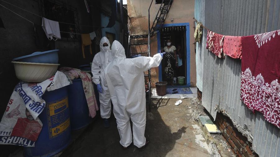 A snack vendor walks in a lane as health workers arrive to screen people for COVID-19 symptoms at a slum in Mumbai, India, Friday, July 10, 2020. India has overtaken Russia to become the third worst-affected nation by the coronavirus pandemic. (AP Photo/Rafiq Maqbool)