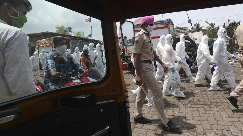 A snack vendor walks in a lane as health workers arrive to screen people for COVID-19 symptoms at a slum in Mumbai, India, Friday, July 10, 2020. India has overtaken Russia to become the third worst-affected nation by the coronavirus pandemic. (AP Photo/Rafiq Maqbool)