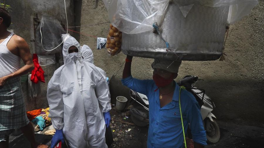 A snack vendor walks in a lane as health workers arrive to screen people for COVID-19 symptoms at a slum in Mumbai, India, Friday, July 10, 2020. India has overtaken Russia to become the third worst-affected nation by the coronavirus pandemic. (AP Photo/Rafiq Maqbool)
