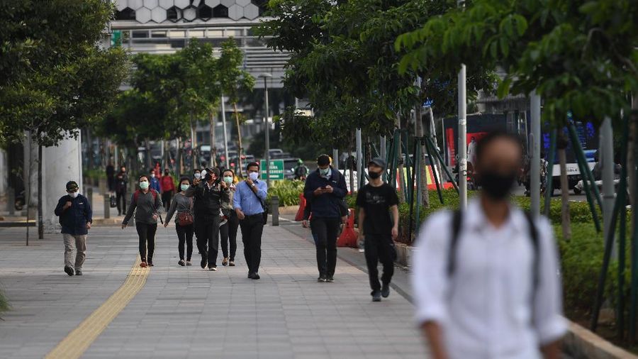 Sejumlah pekerja berjalan usai bekerja dengan latar belakang gedung perkantoran di Jl Jenderal Sudirman, Jakarta, Kamis (16/4/2020). Pemprov DKI Jakarta akan memberikan saksi berupa mencabut perizinan kepada perusahaan yang tetap beroperasi di masa Pembatasan Sosial Berskala Besar (PSBB) kecuali delapan sektor yang memang diizinkan. ANTARA FOTO/Akbar Nugroho Gumay/aww.