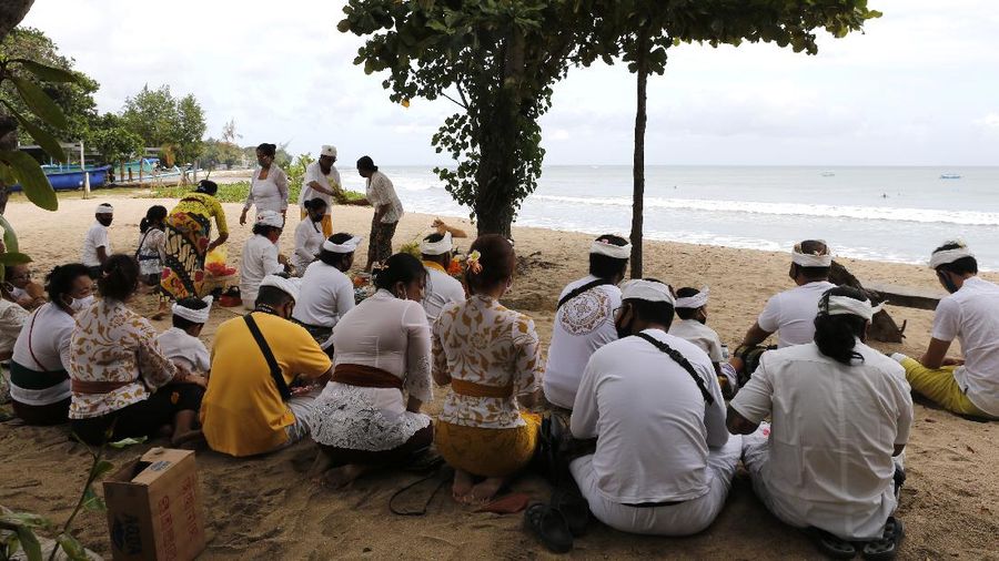 Balinese Hindu gather during a ritual at Kuta beach, Bali, Indonesia on Thursday, July 9, 2020. Indonesia's resort island of Bali reopened after a three-month virus lockdown Thursday, allowing local people and stranded foreign tourists to resume public activities before foreign arrivals resume in September.(AP Photo/Firdia Lisnawati)