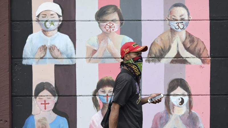 People wearing face masks as a precaution against the new coronavirus walk on a street in Jakarta, Indonesia, Tuesday, July 7, 2020. (AP Photo/Achmad Ibrahim)