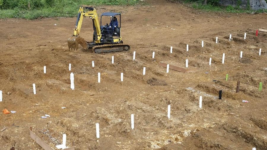 A soldier of 14th Regional Military Command/Hasanuddin manning a backhoe takes a break at a cemetery prepared for people who presumably died of COVID-19, in Makassar, South Sulawesi, Indonesia Saturday, June 20, 2020. As Indonesia’s virus death toll rises, the world’s most populous Muslim country finds itself at odds with protocols put in place by the government to handle the bodies of victims of the pandemic. This has led to increasing incidents of bodies being taken from hospitals, rejection of COVID-19 health and safety procedures, and what some experts say is a lack of communication from the government. (AP Photo/Masyudi Syachban Firmansyah)