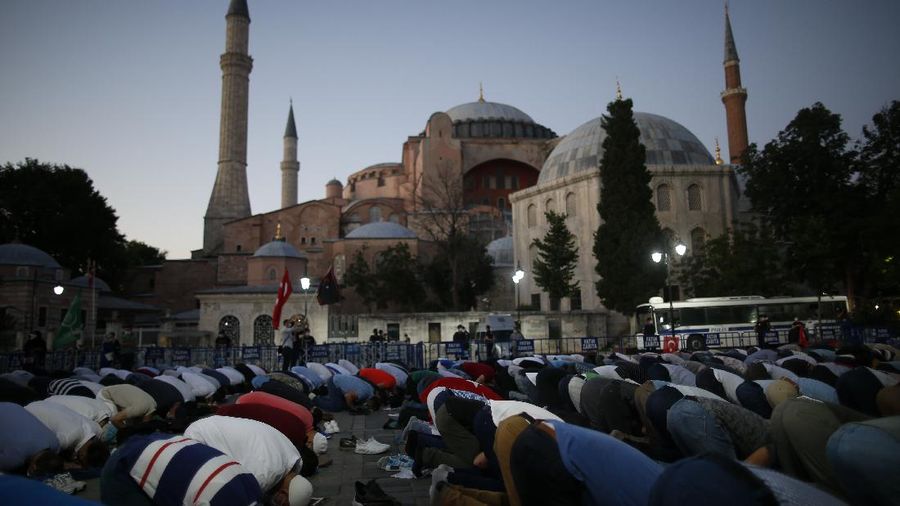Muslims offer their evening prayers outside the Byzantine-era Hagia Sophia, one of Istanbul's main tourist attractions in the historic Sultanahmet district of Istanbul, following Turkey's Council of State's decision, Friday, July 10, 2020. Turkey's highest administrative court issued a ruling Friday that paves the way for the government to convert Hagia Sophia - a former cathedral-turned-mosque that now serves as a museum - back into a Muslim house of worship. The Council of State threw its weight behind a petition brought by a religious group and annulled a 1934 cabinet decision that changed the 6th century building into a museum. (AP Photo/Emrah Gurel)