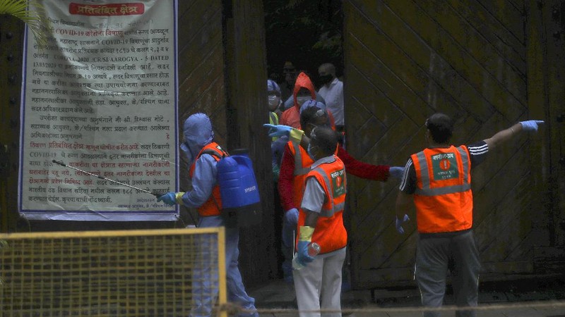 Civic workers sanitize the entrance of Bollywood superstar Amitabh Bachchan's residence after Bachchan and his son tested positive for the coronavirus and were hospitalized in Mumbai, India, Sunday, July 12, 2020. (AP Photo/Rafiq Maqbool)