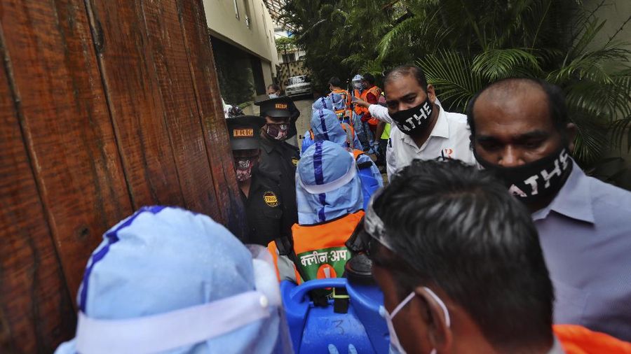Civic workers sanitize the entrance of Bollywood superstar Amitabh Bachchan's residence after Bachchan and his son tested positive for the coronavirus and were hospitalized in Mumbai, India, Sunday, July 12, 2020. (AP Photo/Rafiq Maqbool)