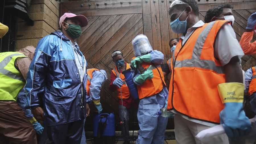 Civic workers sanitize the entrance of Bollywood superstar Amitabh Bachchan's residence after Bachchan and his son tested positive for the coronavirus and were hospitalized in Mumbai, India, Sunday, July 12, 2020. (AP Photo/Rafiq Maqbool)