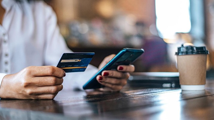 Pay for goods by credit card through a smartphone in a coffee shop.