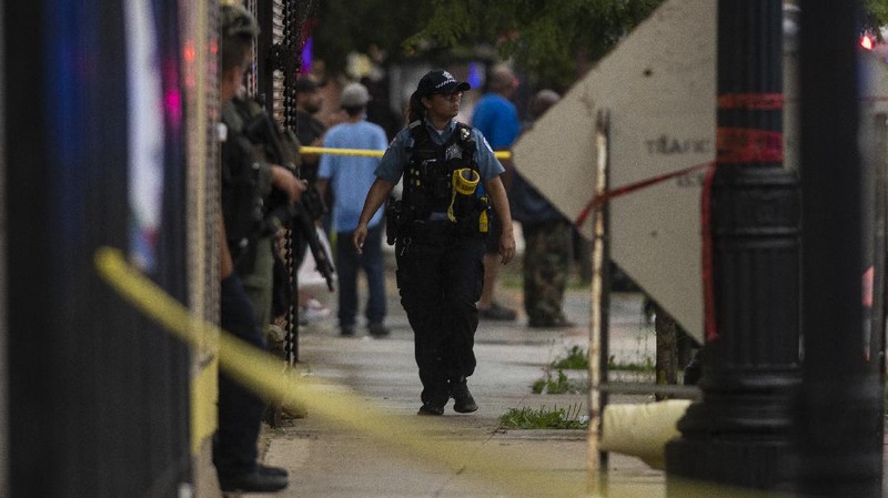 Chicago police investigate the scene of a mass shooting where more then a dozen people were shot in the Gresham neighborhood, of Chicago, Tuesday, July 21, 2020.  (Tyler LaRiviere/Chicago Sun-Times via AP)