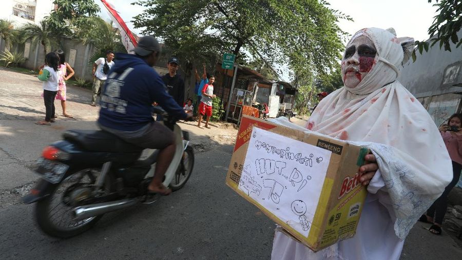 Seorang pemuda karang taruna mengenakan kostum pocong saat meminta sumbangan di kawasan Jombang, Tangerang Selatan, Rabu (22/7/2020). (CNBC Indonesia/ANdrean Kristianto)