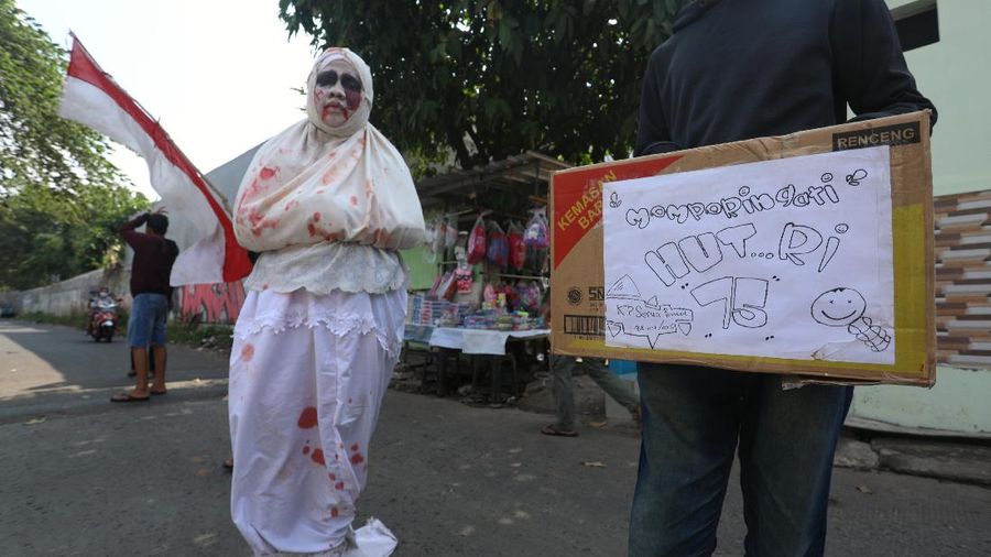 Seorang pemuda karang taruna mengenakan kostum pocong saat meminta sumbangan di kawasan Jombang, Tangerang Selatan, Rabu (22/7/2020). (CNBC Indonesia/ANdrean Kristianto)
