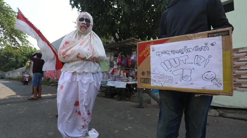 Seorang pemuda karang taruna mengenakan kostum pocong saat meminta sumbangan di kawasan Jombang, Tangerang Selatan, Rabu (22/7/2020). (CNBC Indonesia/ANdrean Kristianto)
