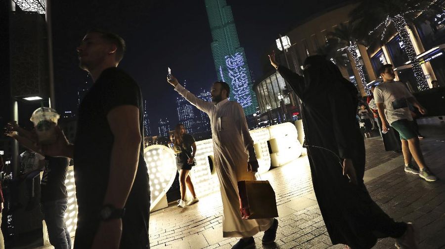Saudi people dance with their national flag as they are celebrating the Saudi Arabia's 89th National Day in Dubai, United Arab Emirates, Monday, Sept. 23, 2019. (AP Photo/Kamran Jebreili)