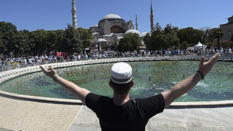 A man waves a Turkish flag outside the Byzantine-era Hagia Sophia, in the historic Sultanahmet district of Istanbul, Friday, July 24, 2020. Hundreds of Muslim faithful were making their way to Istanbul's landmark monument Friday to take part in the first prayers in 86 years at the structure that was once Christendom's most significant cathedral and the 