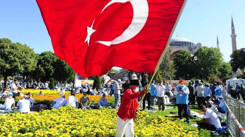 A man waves a Turkish flag outside the Byzantine-era Hagia Sophia, in the historic Sultanahmet district of Istanbul, Friday, July 24, 2020. Hundreds of Muslim faithful were making their way to Istanbul's landmark monument Friday to take part in the first prayers in 86 years at the structure that was once Christendom's most significant cathedral and the 