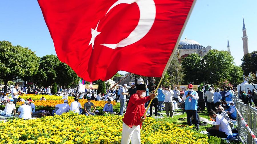 A man waves a Turkish flag outside the Byzantine-era Hagia Sophia, in the historic Sultanahmet district of Istanbul, Friday, July 24, 2020. Hundreds of Muslim faithful were making their way to Istanbul's landmark monument Friday to take part in the first prayers in 86 years at the structure that was once Christendom's most significant cathedral and the
