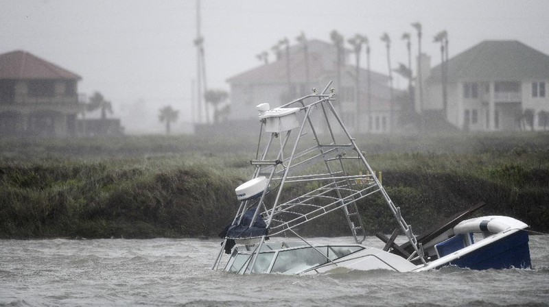A boat sinks in the Packery Channel during Hurricane Hanna, Saturday, July 25, 2020, in North Padre Island, Texas. The Category 1 storm continued to strengthen before reaching Padre Island at 5 p.m. Saturday. (Annie Rice/Corpus Christi Caller-Times via AP)