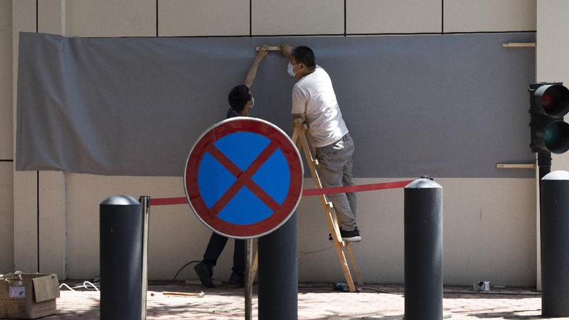 Workers prepare to cover up the areas where the signage used to show the location as United States Consulate in Chengdu in southwest China's Sichuan province on Monday, July 27, 2020. Chinese authorities took control of the former U.S. consulate in the southwestern Chinese city of Chengdu on Monday after it was ordered closed in retaliation for a U.S. order to vacate the Chinese Consulate in Houston. (AP Photo/Ng Han Guan)
