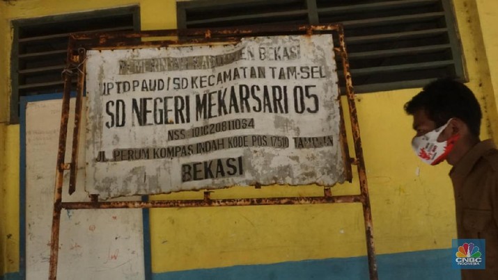 Pegawai mengamati bagian atap bangunan SDN Mekarsari 05 yang rusak di Tambun, Kabupaten Bekasi, Jawa Barat, Senin (27/7/2020). Menurut pihak sekolah, terdapat dua ruang kelas dan satu ruang guru yang kondisinya rusak dan tidak dapat digunakan lagi sejak tujuh bulan yang lalu. Bangunan ini rusak karena kondisi yang sudah tua. Menurut penjaga sekolah ini dibangun sejak 1984.  Kondisi ruangan dalam kondisi rusak, rata-rata kerusakan pada bagian plafon yang sudah bolong-bolong. 
 (CNBC Indonesia/ Muhammad Sabki)
