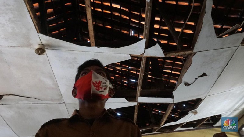 Pegawai mengamati bagian atap bangunan SDN Mekarsari 05 yang rusak di Tambun, Kabupaten Bekasi, Jawa Barat, Senin (27/7/2020). Menurut pihak sekolah, terdapat dua ruang kelas dan satu ruang guru yang kondisinya rusak dan tidak dapat digunakan lagi sejak tujuh bulan yang lalu. Bangunan ini rusak karena kondisi yang sudah tua. Menurut penjaga sekolah ini dibangun sejak 1984.  Kondisi ruangan dalam kondisi rusak, rata-rata kerusakan pada bagian plafon yang sudah bolong-bolong. 
 (CNBC Indonesia/ Muhammad Sabki)