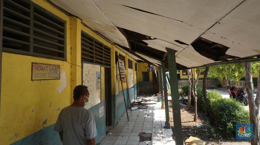 Pegawai mengamati bagian atap bangunan SDN Mekarsari 05 yang rusak di Tambun, Kabupaten Bekasi, Jawa Barat, Senin (27/7/2020). Menurut pihak sekolah, terdapat dua ruang kelas dan satu ruang guru yang kondisinya rusak dan tidak dapat digunakan lagi sejak tujuh bulan yang lalu. Bangunan ini rusak karena kondisi yang sudah tua. Menurut penjaga sekolah ini dibangun sejak 1984.  Kondisi ruangan dalam kondisi rusak, rata-rata kerusakan pada bagian plafon yang sudah bolong-bolong. 
 (CNBC Indonesia/ Muhammad Sabki)