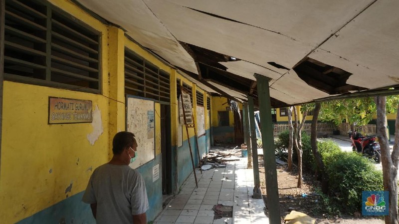 Pegawai mengamati bagian atap bangunan SDN Mekarsari 05 yang rusak di Tambun, Kabupaten Bekasi, Jawa Barat, Senin (27/7/2020). Menurut pihak sekolah, terdapat dua ruang kelas dan satu ruang guru yang kondisinya rusak dan tidak dapat digunakan lagi sejak tujuh bulan yang lalu. Bangunan ini rusak karena kondisi yang sudah tua. Menurut penjaga sekolah ini dibangun sejak 1984.  Kondisi ruangan dalam kondisi rusak, rata-rata kerusakan pada bagian plafon yang sudah bolong-bolong. 
 (CNBC Indonesia/ Muhammad Sabki)