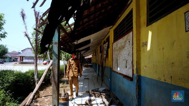 Pegawai mengamati bagian atap bangunan SDN Mekarsari 05 yang rusak di Tambun, Kabupaten Bekasi, Jawa Barat, Senin (27/7/2020). Menurut pihak sekolah, terdapat dua ruang kelas dan satu ruang guru yang kondisinya rusak dan tidak dapat digunakan lagi sejak tujuh bulan yang lalu. Bangunan ini rusak karena kondisi yang sudah tua. Menurut penjaga sekolah ini dibangun sejak 1984.  Kondisi ruangan dalam kondisi rusak, rata-rata kerusakan pada bagian plafon yang sudah bolong-bolong. 
 (CNBC Indonesia/ Muhammad Sabki)