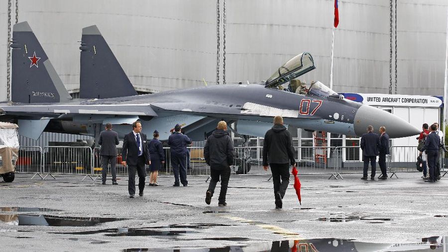 Visitors look at a Sukhoi SU-35 made by United Aircraft Corporation, displayed at the 50th Paris Air Show at Le Bourget airport, north of Paris, Thursday June 20, 2013. (AP Photo/Remy de la Mauviniere)