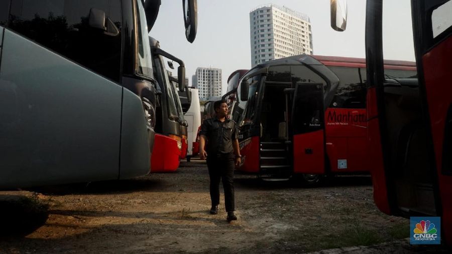 Petugas merapihkan deretan bus di Pool Bus Pariwisata Kawasan Tanjung Barat, Jakarta Selatan, Selasa (28/7/2020). Masih diberlakukannya Pembatasan Sosial Bersekala Besar (PSBB) dan penutupan tempat rekreasi akibat Covid-19, berimbas pada jasa transportasi pariwisata. 

Penutupan obyek wisata dan imbauan untuk tidak ke tempat keramaian demi mencegah penyebaran corona (covid-19) membuat Perusahaan Otobus (PO) pariwisata mengandangkan armadanya. Padahal, momen sebelum datangnya Ramadhan merupakan waktunya para pemilik perusahaan otobus panen rezeki.
PO terpaksa mengandangkan armadanya karena berbagai acara keluar kota dibatalkan. Permasalahan tak berhenti di situ saja, bayang-bayang setoran cicilan ke perusahaan leasing juga menghantui para pemilik PO ini. 

Fajar, Head Marketing bus Manhattan, pada CNBC Indonesia, menjelaskan para usaha bus sejak pandemi ini terpuruk. Apalagi, menurut Fajar, pesanan bus biasanya sudah ramai lagi pada H-7 Lebaran kemarin.

Dengan kondisi seperti ini, banyak bus yang dikandangkan, akibatnya membuat pemasukan tidak ada.

