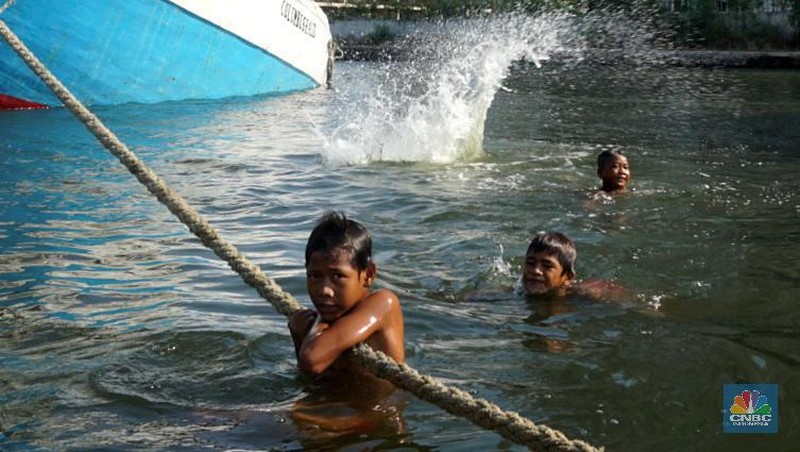 Sayup suara ombak menyusup hingga ke ruang-ruang sempit Kapal yang tengah bersandar di Pelabuhan Sunda Kelapa, Jakarta Utara, Rabu (29/7/2020) petang itu. Sejumlah anak dengan berani tengah asik melompat bergantian dari atas kapal, sambil berteriak.
Sunda Kelapa adalah nama pelabuhan yang berada di ujung utara Jakarta. Pelabuhan ini sudah ada sejak ratusan tahun lalu. Pada zaman kerajaan, Sunda Kelapa adalah pusat perdagangan. Kini, meski telah dimakan usia, pelabuhan ini masih tetap ramai.
Banyak orang mengais rezeki di Pelabuhan Sunda Kelapa. Ada pedagang, nelayan, Anak Buah Kapal (ABK), pemberi jasa sampan, hingga buruh angkut. Semua tumpah ruah menjadi satu. Namun bagi anak-anak sunda kelapa adalah tempat paling asik untuk bermain.

Pelabuhan Sunda Kelapa lambat laun tidak terlihat sesibuk saat masa jayanya. Kini, pelabuhan tersebut dikelola oleh PT Pelindo II dan tidak mengantongi sertifikasi International Ship and Port Security karena sifat pelayanan jasanya hanya untuk melayani kapal antar pulau di dalam negeri.

Dari sisi ekonomi pelabuhan ini masih cukup strategis, mengingat berdekatan dengan pusat-pusat perdagangan di Jakarta seperti Glodok, Pasar Pagi, Mangga Dua, dan lain-lainnya. Menjadi buruh kuli angkut mungkin bukan hal yang dicita-citakn oleh banyak orang. Namun ketika tidak ada lagi keahlian yang bisa ditawarkan selain tenaga kasar maka menjadi buruh kasar sebagai kuli angkut pun harus dijalani.

Setidaknya ini yang tertangkap saat melihat potret para kuli angkut di Pelabuhan Sunda Kelapa Jakarta Utara. Dalam sehari para pekerja kuli angkut ini mampu membongkar muatan dengan berat total 300ton. Beban sebesar ini dikerjakan oleh 20an orang pekerja.  (CNBC Indonesia/ Muhammad Sabki)
