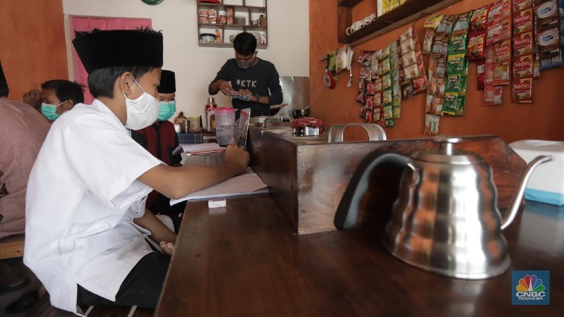 Gerai warung kopi di Tangerang Selatan menyediakan fasilitas internet gratis untuk membantu para pelajar mengikuti belajar daring. Kamis, (30/7/20). (CNBC Indonesia/Tri Susilo)

Warung kopi (warkop) di kawasan Pondok Aren, Tangerang Selatan, sediakan internet gratis untuk siswa yang kesulitan mengikuti proses belajar daring.

Rizki, selaku pemilik warung kopi mengaku tergerak untuk membantu para siswa di sekitar tempat usahanya lantaran banyak yang kesulitan mengikuti kegiatan belajar jarak jauh karena kesulitan membeli kuota internet, atau bahkan hanya memiliki satu ponsel yang digunakan orangtua mereka untuk bekerja.   

Kita kan baru mulai hari ini, alhamdulillah cukup tinggi antusiasnya. Karena kebanyakan orangtuanya cuma punya satu ponsel. Kayak yang kerjanya ojol, jadi dibawa buat tarik penumpang,