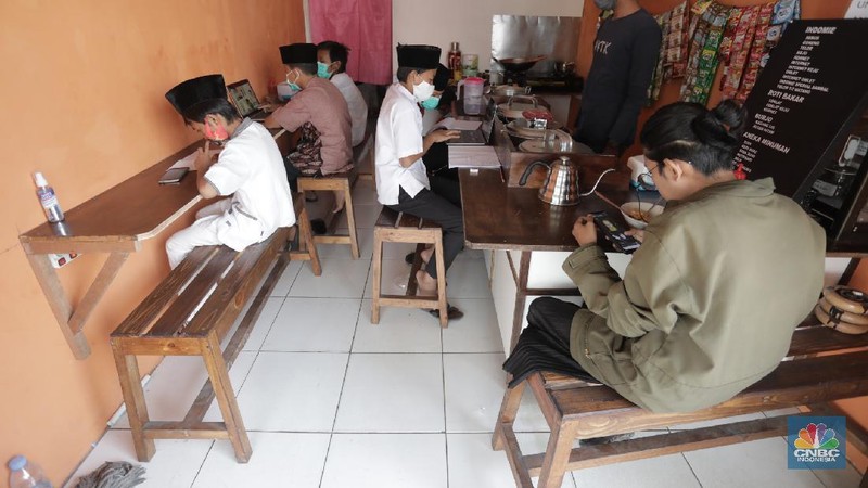 Gerai warung kopi di Tangerang Selatan menyediakan fasilitas internet gratis untuk membantu para pelajar mengikuti belajar daring. Kamis, (30/7/20). (CNBC Indonesia/Tri Susilo)

Warung kopi (warkop) di kawasan Pondok Aren, Tangerang Selatan, sediakan internet gratis untuk siswa yang kesulitan mengikuti proses belajar daring.

Rizki, selaku pemilik warung kopi mengaku tergerak untuk membantu para siswa di sekitar tempat usahanya lantaran banyak yang kesulitan mengikuti kegiatan belajar jarak jauh karena kesulitan membeli kuota internet, atau bahkan hanya memiliki satu ponsel yang digunakan orangtua mereka untuk bekerja.   

Kita kan baru mulai hari ini, alhamdulillah cukup tinggi antusiasnya. Karena kebanyakan orangtuanya cuma punya satu ponsel. Kayak yang kerjanya ojol, jadi dibawa buat tarik penumpang,