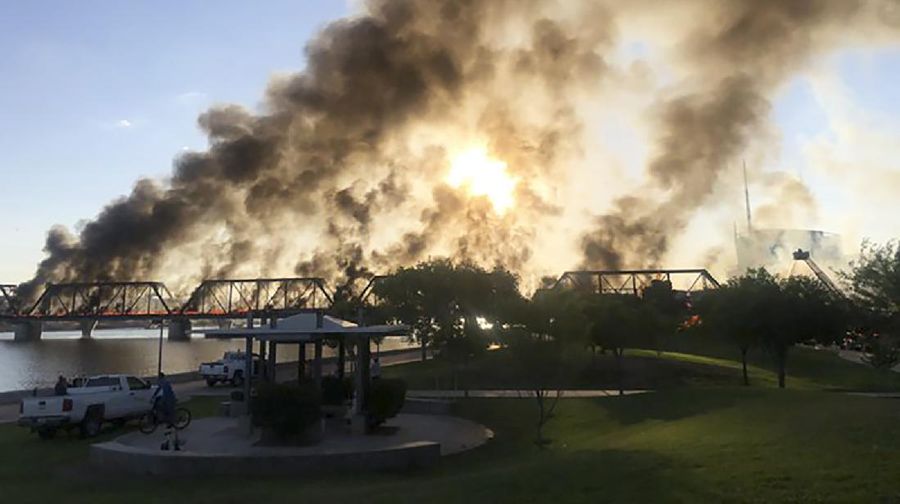 Smoke fills the sky at the scene of a train derailment in Tempe, Ariz., on Wednesday, July 29, 2020. Officials say a freight train traveling on a bridge that spans a lake in the Phoenix suburb derailed and set the bridge ablaze and partially collapsing the structure.  There were no immediate reports of any leaks. (Daniel Coronado via AP)