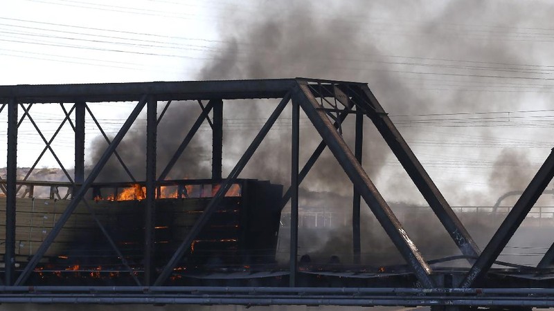 Smoke fills the sky at the scene of a train derailment in Tempe, Ariz., on Wednesday, July 29, 2020. Officials say a freight train traveling on a bridge that spans a lake in the Phoenix suburb derailed and set the bridge ablaze and partially collapsing the structure.  There were no immediate reports of any leaks. (Daniel Coronado via AP)