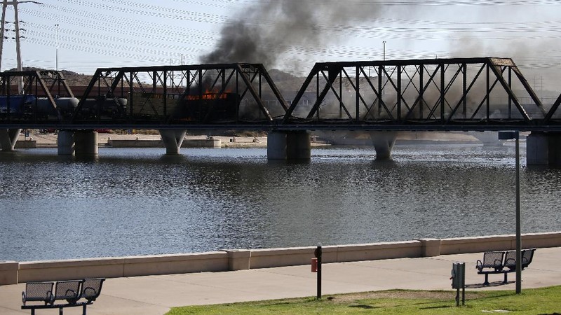 Smoke fills the sky at the scene of a train derailment in Tempe, Ariz., on Wednesday, July 29, 2020. Officials say a freight train traveling on a bridge that spans a lake in the Phoenix suburb derailed and set the bridge ablaze and partially collapsing the structure.  There were no immediate reports of any leaks. (Daniel Coronado via AP)