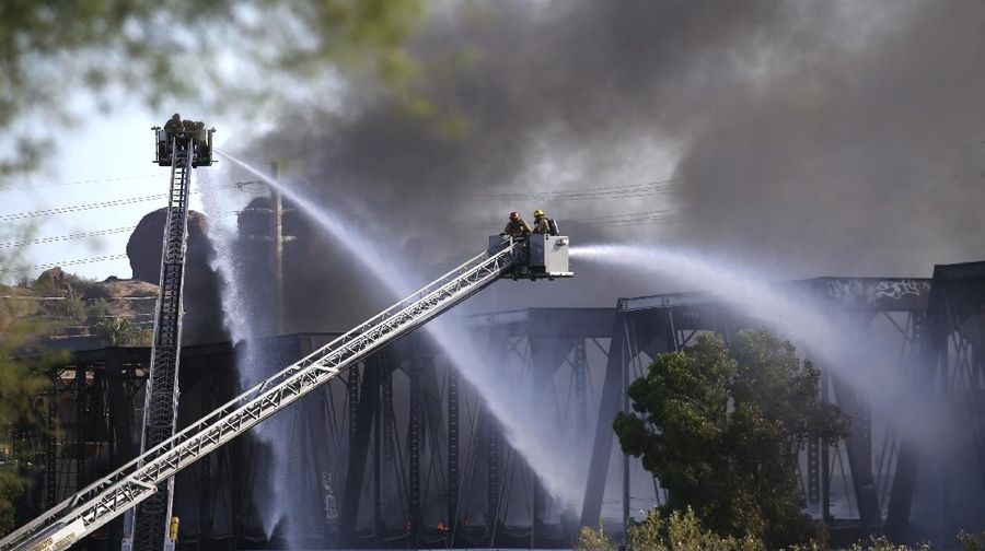 Smoke fills the sky at the scene of a train derailment in Tempe, Ariz., on Wednesday, July 29, 2020. Officials say a freight train traveling on a bridge that spans a lake in the Phoenix suburb derailed and set the bridge ablaze and partially collapsing the structure.  There were no immediate reports of any leaks. (Daniel Coronado via AP)