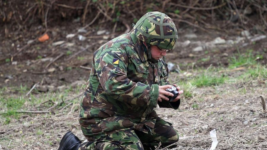 A soldier from the British Army takes a photo of a piece of wreckage from the car bomb that exploded outside Newtownhamilton Police Station, Northern Ireland, Friday, April, 23, 2010. Irish Republican Army dissidents fired gunshots and detonated a car bomb outside a security base in a Northern Ireland border village, injuring three people, police said Friday. The attack outside the heavily fortified Newtownhamilton police station is the third in the British territory this year by splinter IRA groups. They oppose Northern Ireland's peace process and the Catholic-Protestant government it forged. (AP Photo/Peter Morrison)