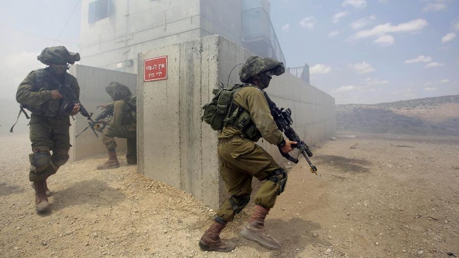Israeli soldiers run during an exercise which simulates warfare in the Gaza Strip, at an army base in the south of Israel, Monday, July 14, 2014. Israel began its campaign against militants in the Hamas-controlled Gaza last Tuesday, saying it was responding to heavy rocket fire from the densely populated territory. The military says it has launched more than 1,300 airstrikes since then, while Palestinian militants have launched nearly 1,000 rockets at Israel. (AP Photo/Tsafrir Abayov)