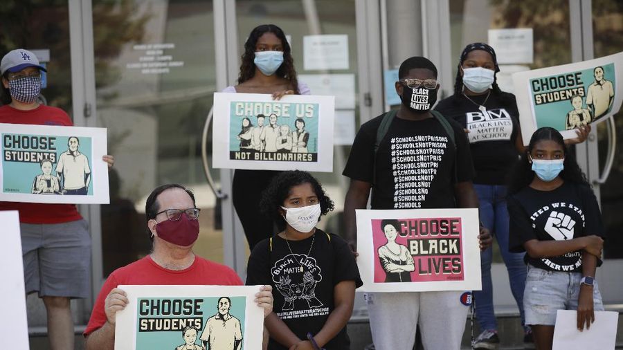 Demonstrators hold signs during a protest Monday, Aug. 3, 2020, in Los Angeles. Parents, students, and teachers held a press conference and car caravan to call for a safe, fully funded, and racially just approach to reopening of Los Angeles schools. (AP Photo/Marcio Jose Sanchez)